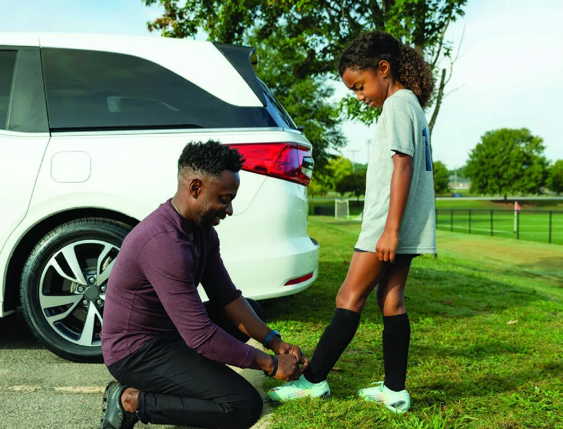 Father helping his daughter beside their minivan